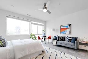 a bedroom with a bed and a couch in front of a window