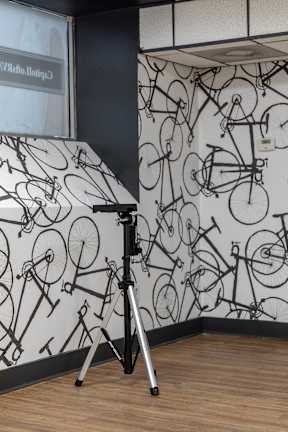 A tripod stands in front of a wall with bicycle wallpaper.