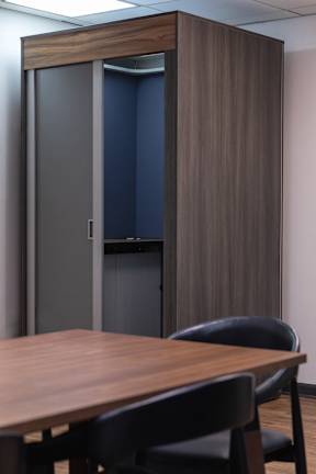 A room with a brown table and two chairs with a brown and grey wardrobe.