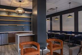 A modern kitchen with a bar area and chairs.