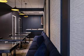 A modern dining area with dark walls and blue couches.