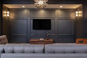 A grey sofa in front of a grey wall with a television.
