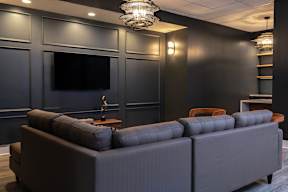 A modern living room with a grey sofa and a flat screen TV mounted on the wall.