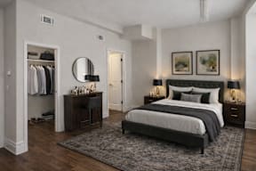 A bedroom with a large bed, a dressing area, and a rug on the floor.