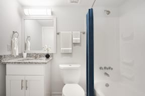 A white bathroom with a toilet, sink, and mirror.