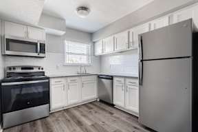 A kitchen with a refrigerator, oven, and microwave.
