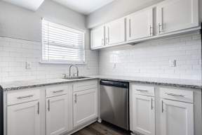 A kitchen with white cabinets and a black dishwasher.