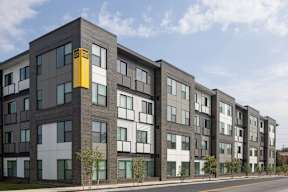 A modern apartment building with a yellow sign on the corner.