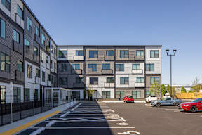 A parking lot in front of a modern building with cars parked.