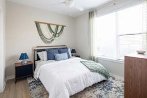 A bedroom with a large bed and a window with blinds.