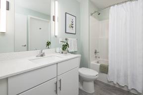 A white bathroom with a toilet, sink, and shower.