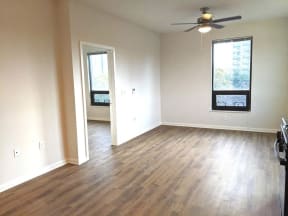 an empty living room with wooden floors and a ceiling fan