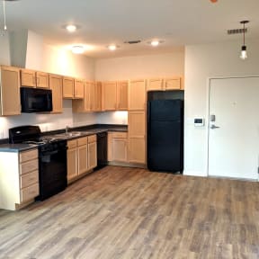 an empty kitchen with wooden floors and black appliances
