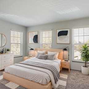 A bedroom with a large bed, two lamps, and two framed pictures on the wall.
