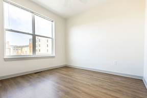 A room with a large window and wooden flooring.