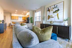 A living room with a grey couch and a large abstract painting on the wall.