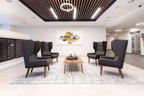 A modern waiting room with grey chairs and a wooden coffee table.