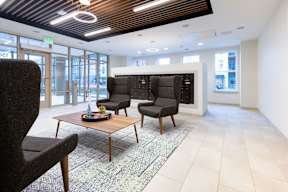 A modern office space with a wooden table and black chairs.
