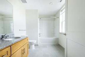 A white bathroom with a marble countertop and a walk-in shower.