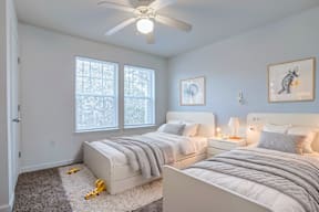A bedroom with two beds and a ceiling fan.