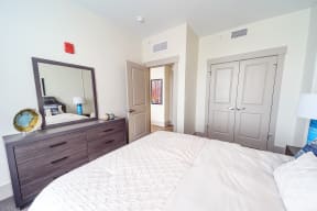 a bedroom with a large bed and a dresser with a mirror