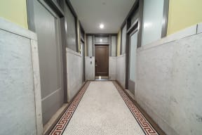 a long hallway with marble walls and floors and a door in the end