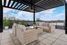 A patio with a wicker sofa and a table with a plant on it.