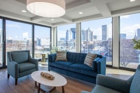 a living room with a blue couch and chairs and a view of the city