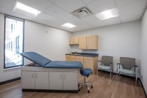a patient room with a blue exam table and two chairs