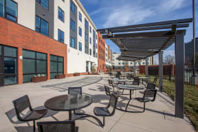 an outdoor patio area with tables and chairs and a building in the background