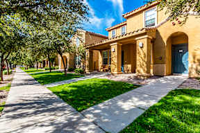 A row of houses with green lawns and trees.