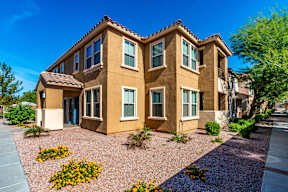 A tan stucco house with a blue door and windows.