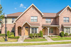 A brick house with a brown door and windows.