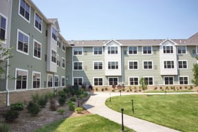 an exterior view of an apartment building with a walkway and lawn at Cahill House Senior Apartments in St. Louis, MO