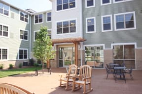 a patio with chairs and tables in front of a building at Cahill House Senior Apartments in St. Louis, MO