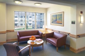 a sitting area with couches and a table with flowers at Cahill House Senior Apartments in St. Louis, MO