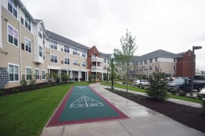 a path leading to an apartment building with a green sidewalk and a green lawn with
