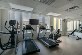 a gym with treadmills and other exercise equipment and windows