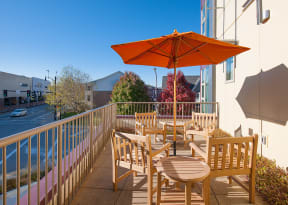 a patio with tables and chairs and an umbrella on a balcony