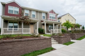 a row of houses with stairs and a sidewalk in front of them at Cornerstone Village Apartments