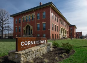 a brick building with a sign for Cornerstone Village Apartments