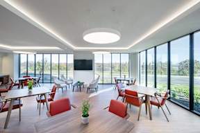 A modern dining room with red chairs and a wooden table.
