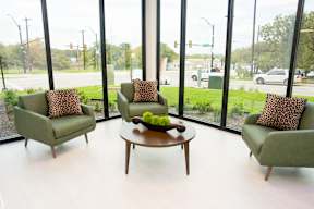 Three chairs and a table are in front of a window with a view of a street.