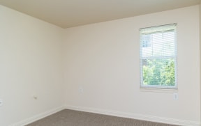a bedroom with a window and white walls at Crawford Square Apartments & Townhomes