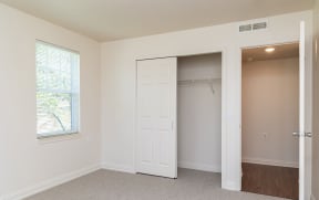 an empty bedroom with a closet and a window at Crawford Square Apartments & Townhomes