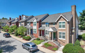 a row of town houses with cars parked in front of them at Crawford Square Apartments & Townhomes