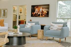 A living room with a fireplace and a painting of a fire on the wall.
