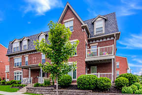 A red brick house with a tree in front.