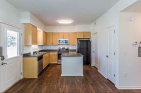 a large kitchen with wooden cabinets and a black refrigerator