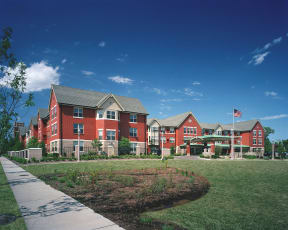 a row of red apartment buildings with an flag in front of them at McCormack House at Forest Park Southeast Senior apartments in St.  Louis, MO